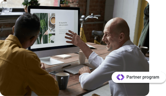 Två män sitter vid ett bord och tittar på en datorskärm med en presentation. Den ena ler och gestikulerar. En knapp med texten 'Affiliateprogram' visas i nedre högra hörnet.